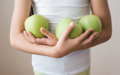Girl in shirt holding three green apples